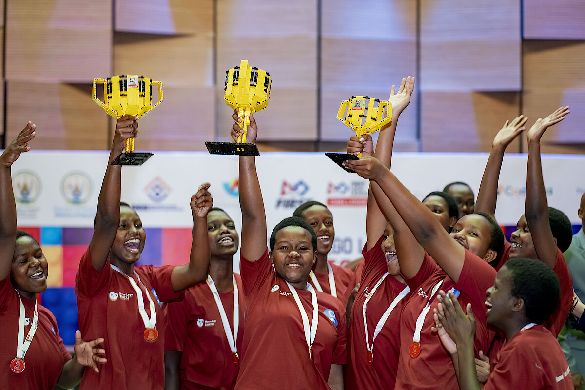 News about Maranyundo GS representing Rwanda at the International First Lego League in Morocco, featuring a photo of students celebrating with Lego trophies.